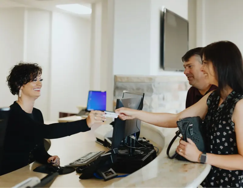 A Hilltop front desk team member welcoming two patients at check-in