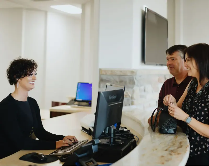 A Hilltop team member greeting two patients at the front desk