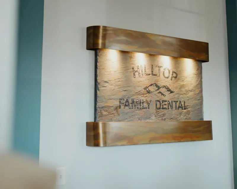 The wooden Hilltop Family Dental sign on the office wall