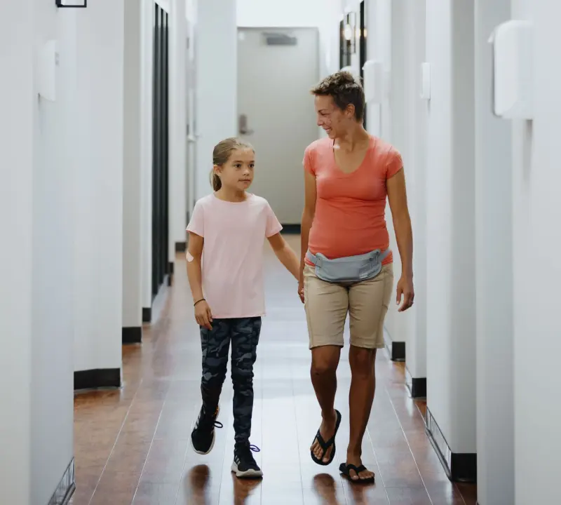A mom and daughter walking down the Hilltop hallway